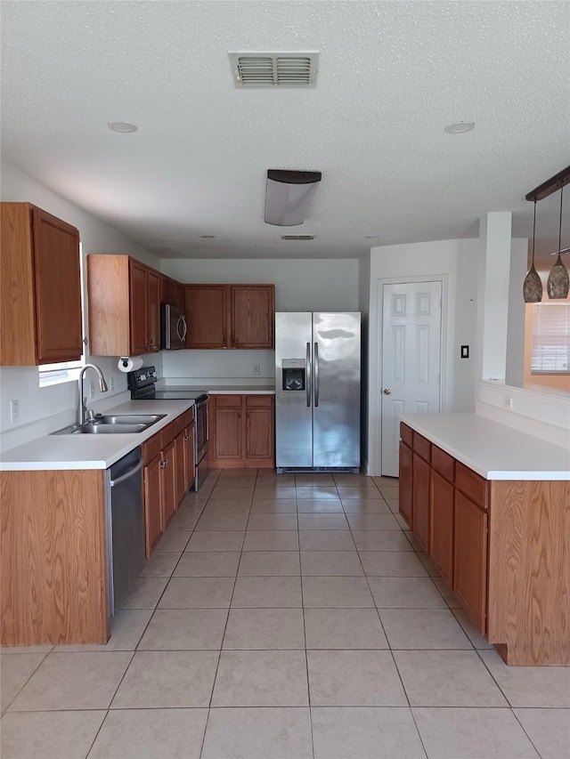 kitchen with decorative light fixtures, sink, light tile patterned floors, stainless steel appliances, and a textured ceiling