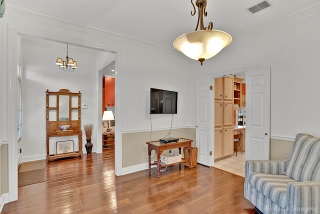 living room featuring ornamental molding, a chandelier, and light hardwood / wood-style flooring