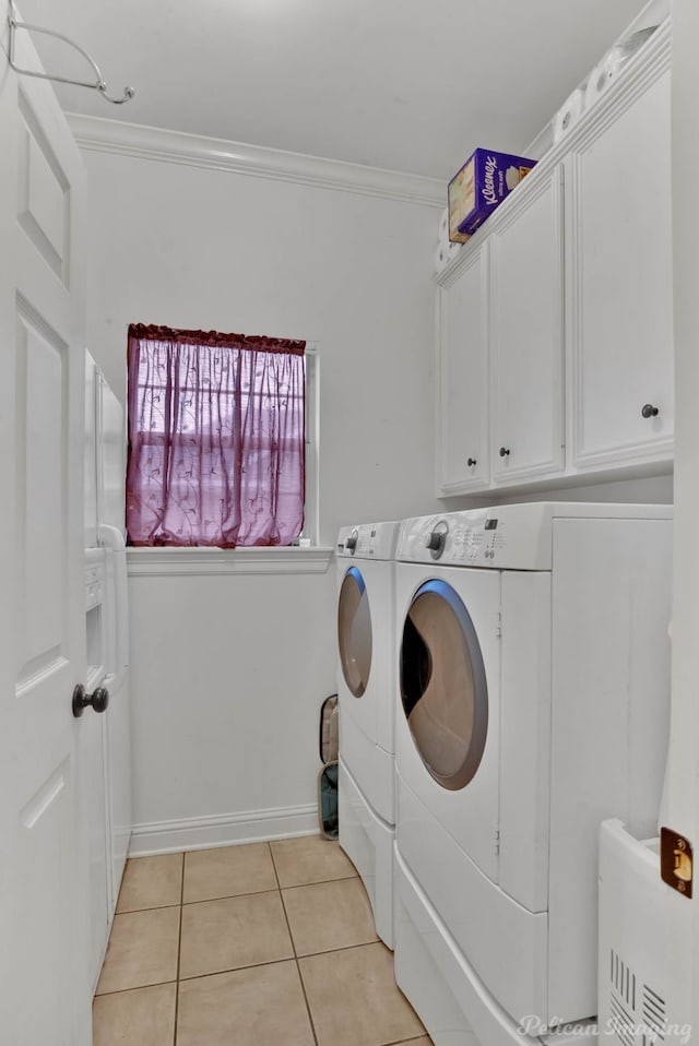 clothes washing area featuring cabinets, washing machine and dryer, ornamental molding, and light tile patterned floors