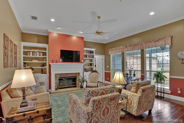 living room featuring dark wood-type flooring, ceiling fan, ornamental molding, and built in features