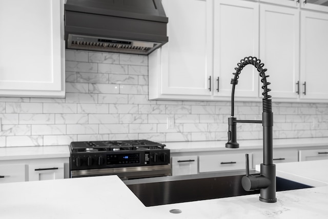 kitchen featuring white cabinetry, backsplash, light stone countertops, and wall chimney exhaust hood