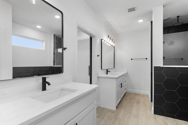 bathroom with vanity, hardwood / wood-style flooring, and tiled shower