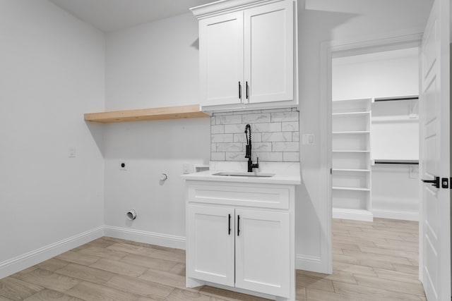 laundry room featuring cabinets, sink, hookup for an electric dryer, and light wood-type flooring