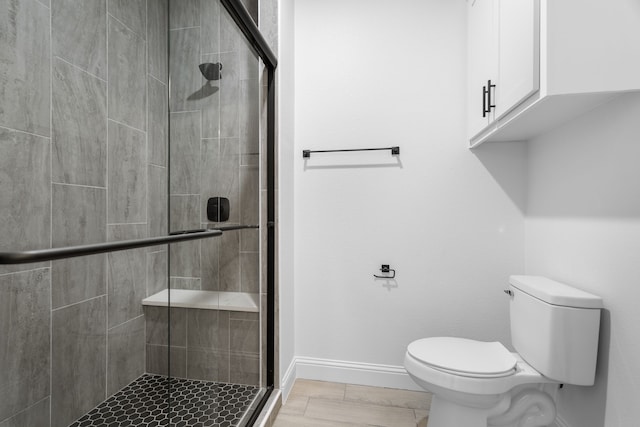 bathroom featuring a shower with shower door and toilet