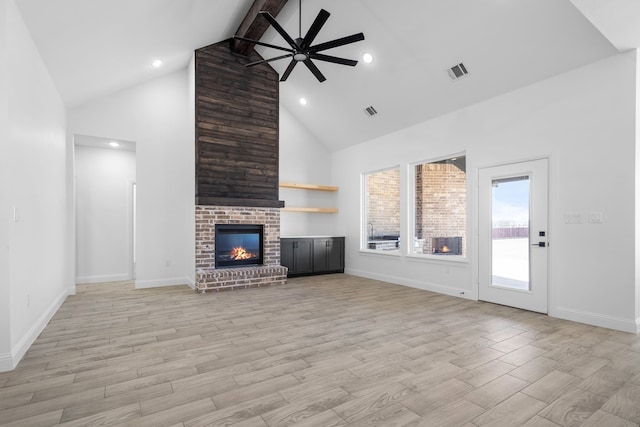 unfurnished living room featuring light hardwood / wood-style flooring, ceiling fan, a fireplace, and beamed ceiling