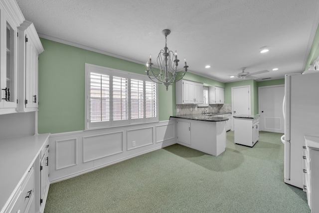 kitchen with ceiling fan with notable chandelier, white cabinetry, decorative backsplash, white fridge, and a textured ceiling