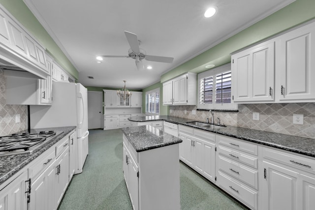 kitchen featuring sink, white cabinetry, a center island, stainless steel gas cooktop, and dark stone counters