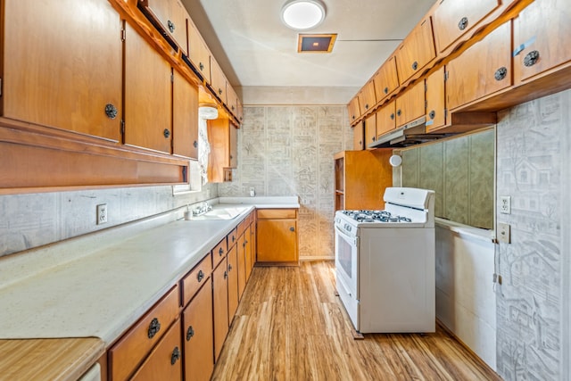 kitchen with white gas range, sink, and light wood-type flooring