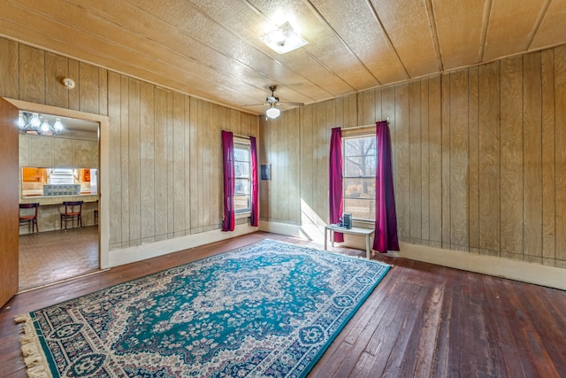 spare room with dark wood-type flooring, ceiling fan, and wooden walls