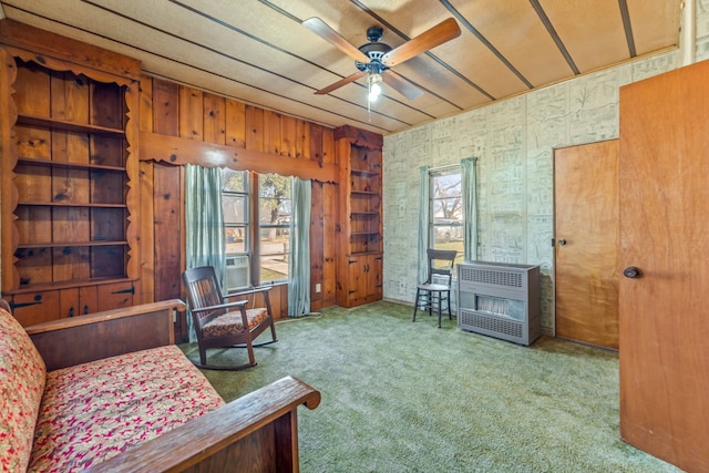 sitting room with ceiling fan, light colored carpet, heating unit, and a wealth of natural light