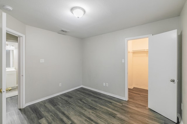 unfurnished bedroom featuring dark hardwood / wood-style floors, a spacious closet, and a closet