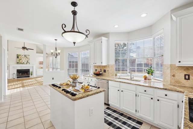 kitchen featuring sink, white cabinetry, a center island, light stone countertops, and stainless steel dishwasher