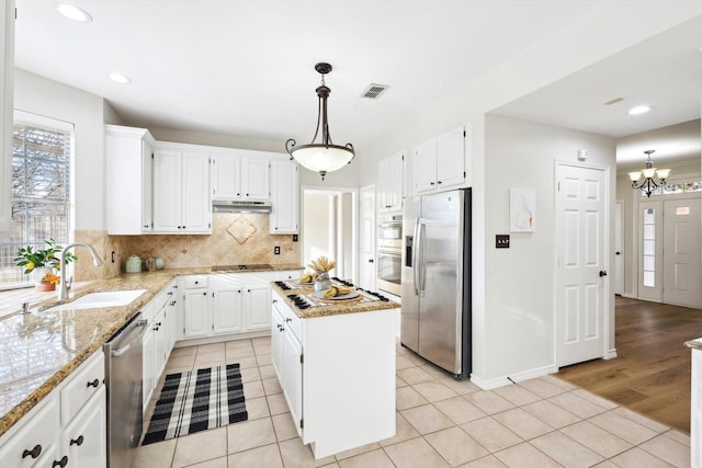 kitchen with sink, stainless steel appliances, a center island, white cabinets, and decorative light fixtures