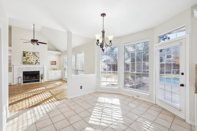 interior space with lofted ceiling, ceiling fan with notable chandelier, and light tile patterned floors