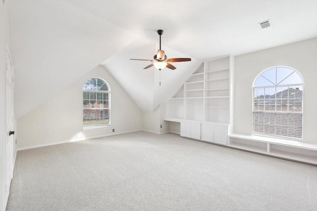 additional living space with ceiling fan, light colored carpet, vaulted ceiling, and built in features