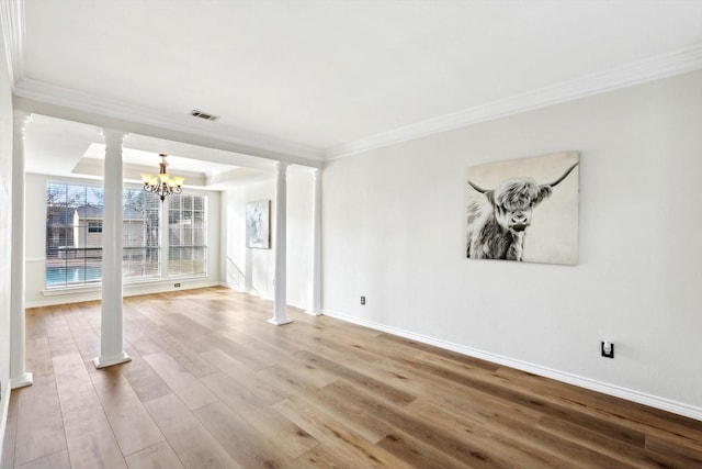 spare room featuring hardwood / wood-style floors, crown molding, a raised ceiling, and ornate columns