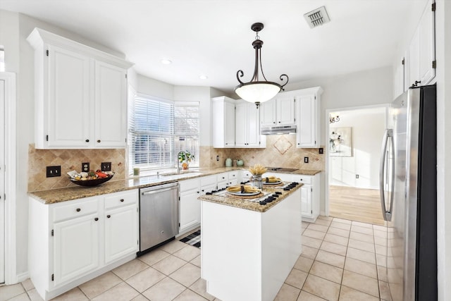 kitchen with light stone counters, light tile patterned floors, a kitchen island, stainless steel appliances, and white cabinets