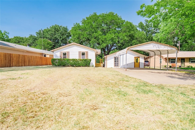 view of front of home with an outbuilding, a front yard, and a carport