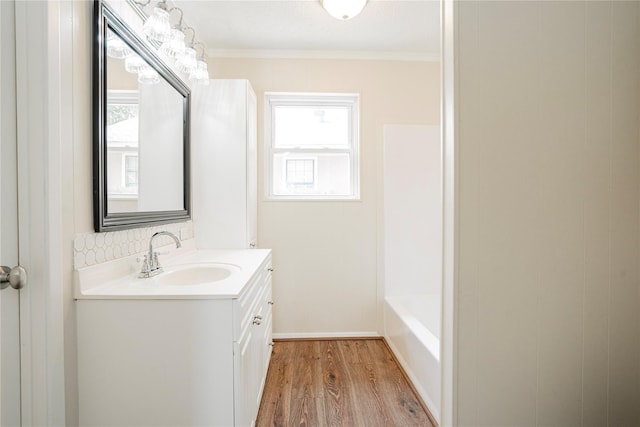 bathroom with vanity, a bath, hardwood / wood-style flooring, and crown molding