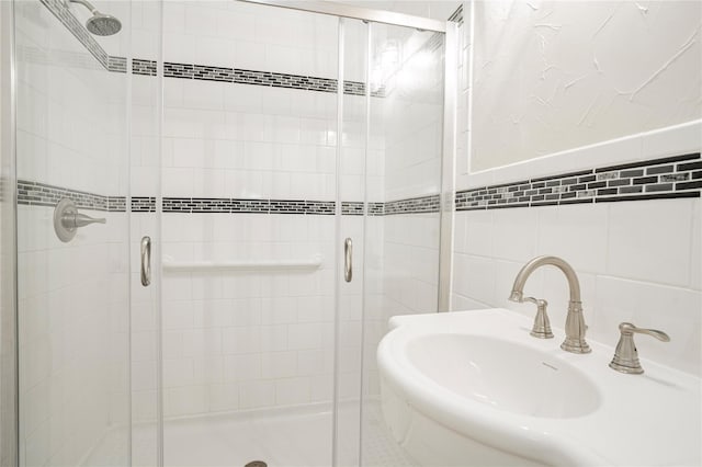 bathroom featuring tile walls, sink, and a shower with shower door