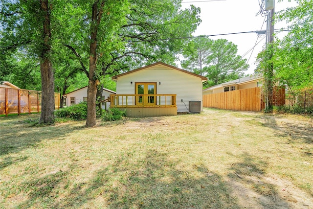 back of property with french doors, a yard, and central AC