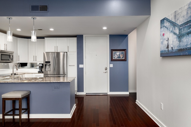 kitchen featuring light stone counters, stainless steel appliances, a sink, visible vents, and white cabinets