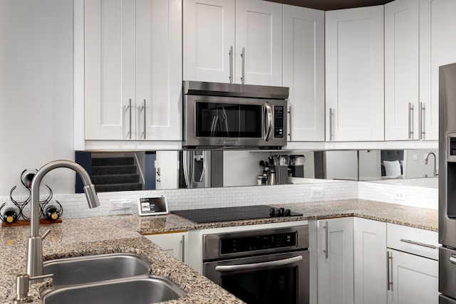 kitchen featuring white cabinetry, appliances with stainless steel finishes, backsplash, and a sink