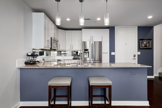 kitchen with visible vents, appliances with stainless steel finishes, light stone counters, a peninsula, and a sink