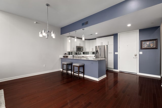 kitchen featuring stainless steel appliances, dark wood-type flooring, a peninsula, a sink, and visible vents