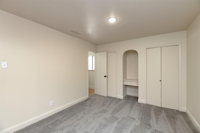 unfurnished bedroom featuring light carpet and two closets