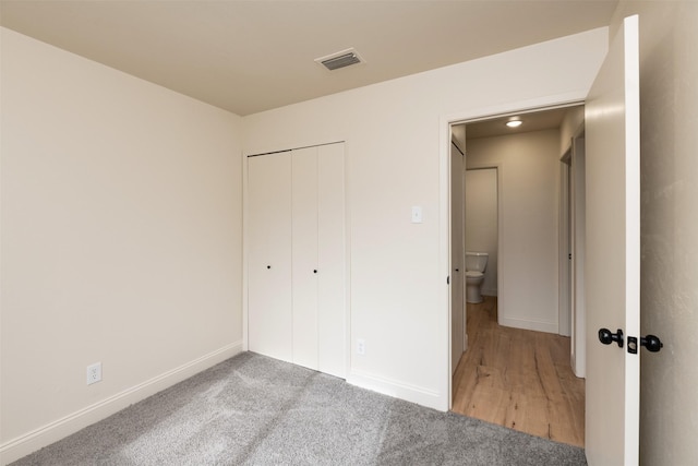 unfurnished bedroom with light colored carpet and a closet