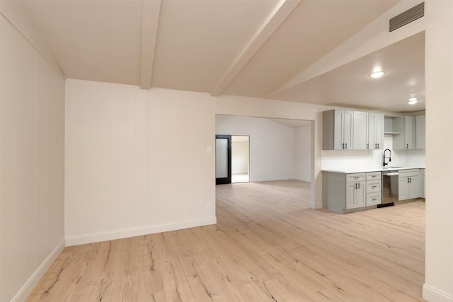 kitchen with sink, gray cabinetry, stainless steel dishwasher, beam ceiling, and light hardwood / wood-style floors