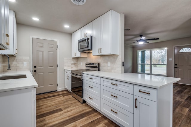 kitchen featuring appliances with stainless steel finishes, dark hardwood / wood-style floors, white cabinetry, sink, and kitchen peninsula