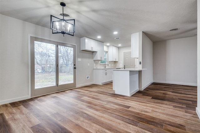 kitchen featuring sink, white cabinetry, tasteful backsplash, light hardwood / wood-style floors, and kitchen peninsula