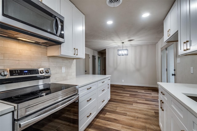 kitchen featuring stainless steel appliances, decorative light fixtures, and white cabinets