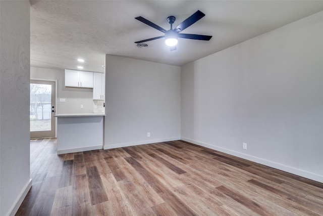 unfurnished living room featuring ceiling fan, a textured ceiling, and light hardwood / wood-style floors