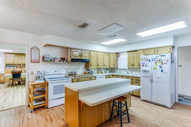 kitchen featuring white appliances, a breakfast bar, a kitchen island, and light wood-type flooring