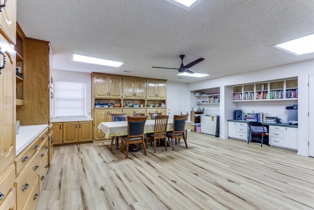 dining room with ceiling fan, light hardwood / wood-style floors, and a textured ceiling