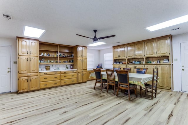 dining area with ceiling fan, light hardwood / wood-style flooring, and a textured ceiling