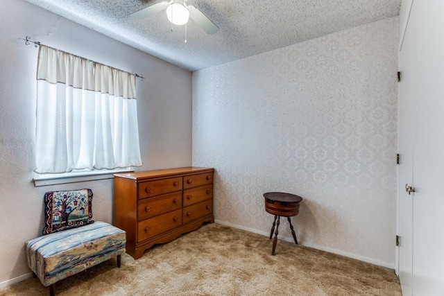 living area featuring light carpet, ceiling fan, and a textured ceiling