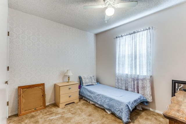 carpeted bedroom with ceiling fan and a textured ceiling