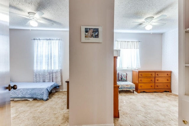 carpeted bedroom featuring ceiling fan and a textured ceiling