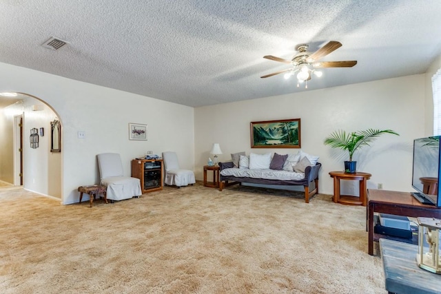 carpeted living room featuring a textured ceiling and ceiling fan