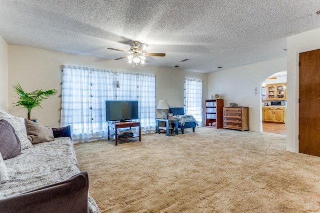 carpeted living room featuring a textured ceiling and ceiling fan