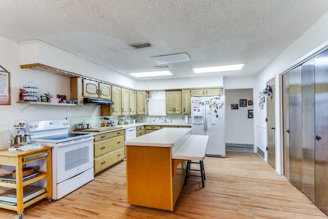 kitchen with a kitchen breakfast bar, a center island, white appliances, light hardwood / wood-style floors, and a textured ceiling