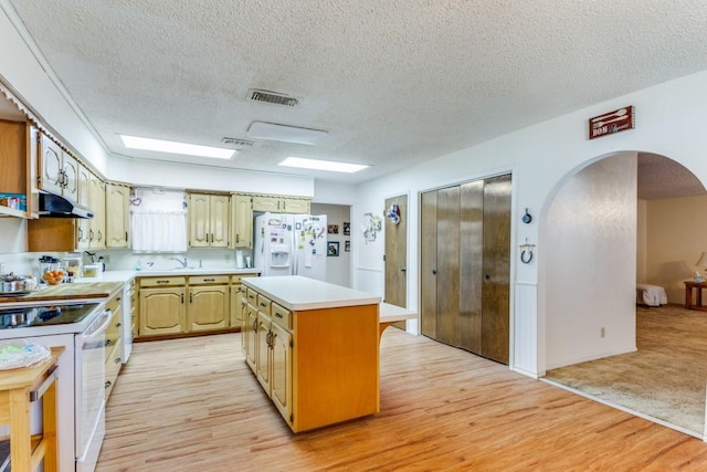 kitchen with white appliances, light hardwood / wood-style floors, a textured ceiling, and a kitchen island