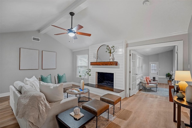 living room with vaulted ceiling with beams, a large fireplace, ceiling fan, and light wood-type flooring