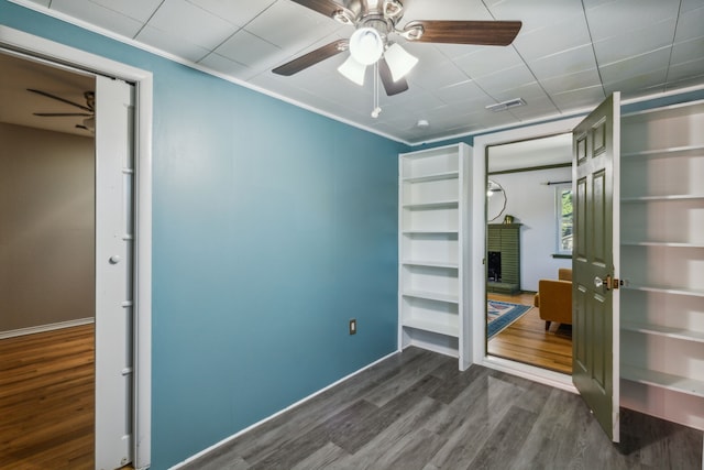 unfurnished bedroom featuring dark wood-type flooring, a fireplace, and crown molding