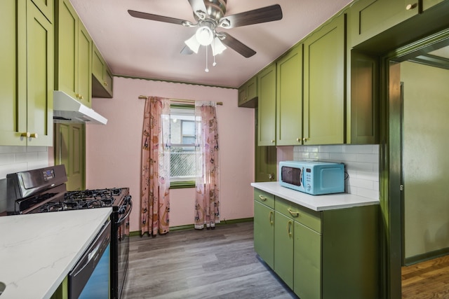 kitchen with light wood-type flooring, green cabinets, light stone counters, and gas range oven