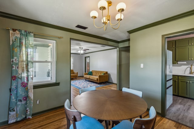 dining room with sink, a notable chandelier, crown molding, and dark hardwood / wood-style floors